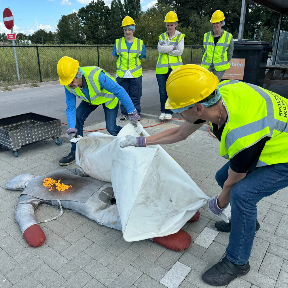 Cursisten gebruiken blusdeken bij persoon in brand, BHV-training België, NedCert Experts.