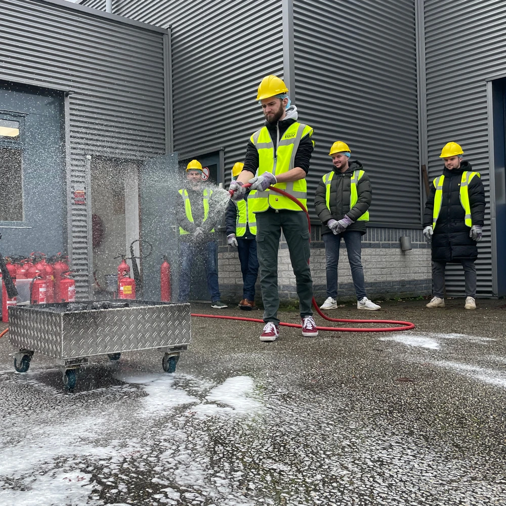 Cursisten blussen brand samen tijdens BHV-training in België, NedCert Experts.