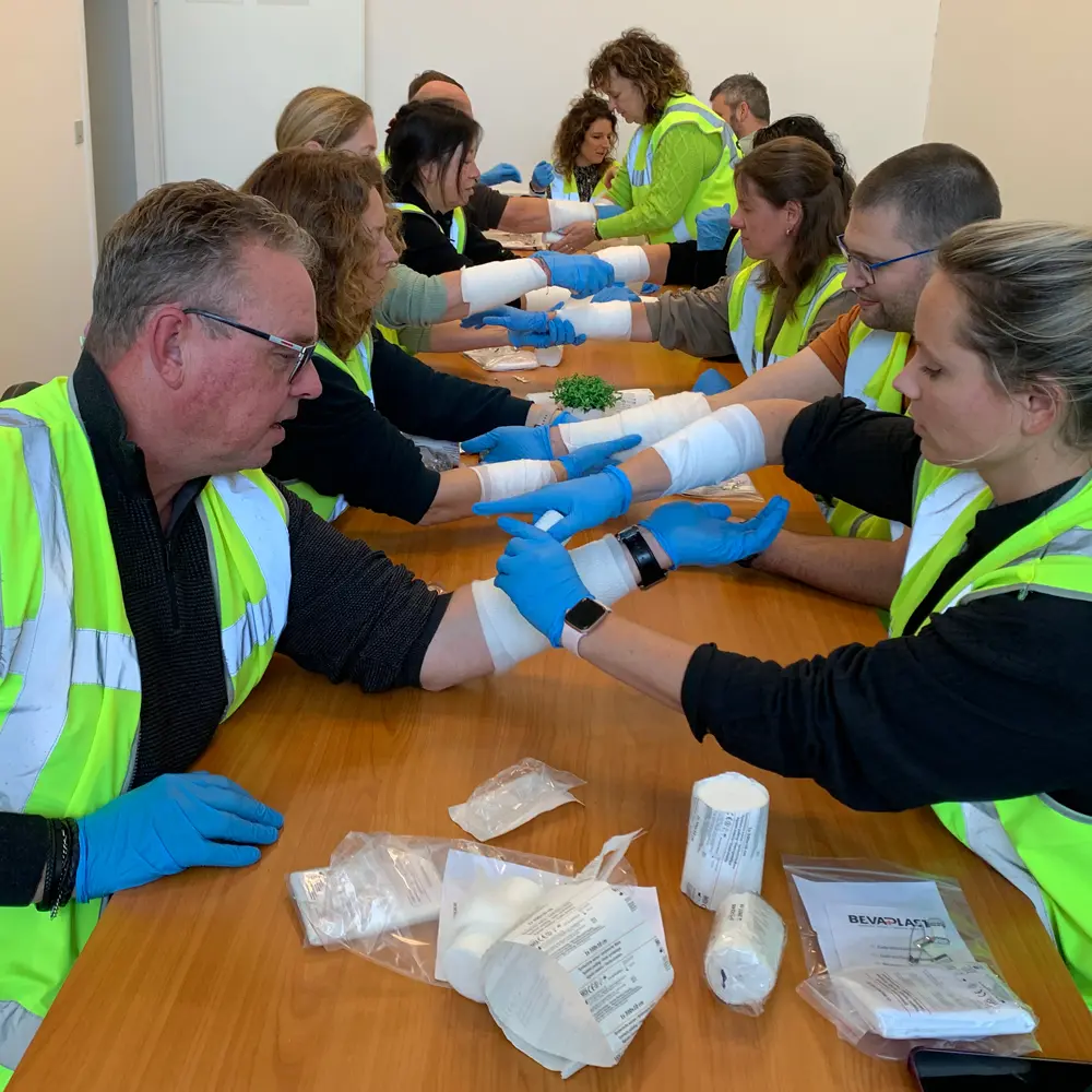 Participants practice bandage application during an ERO course by NedCert Experts, a key first aid skill for emergency response officers in international workplaces.