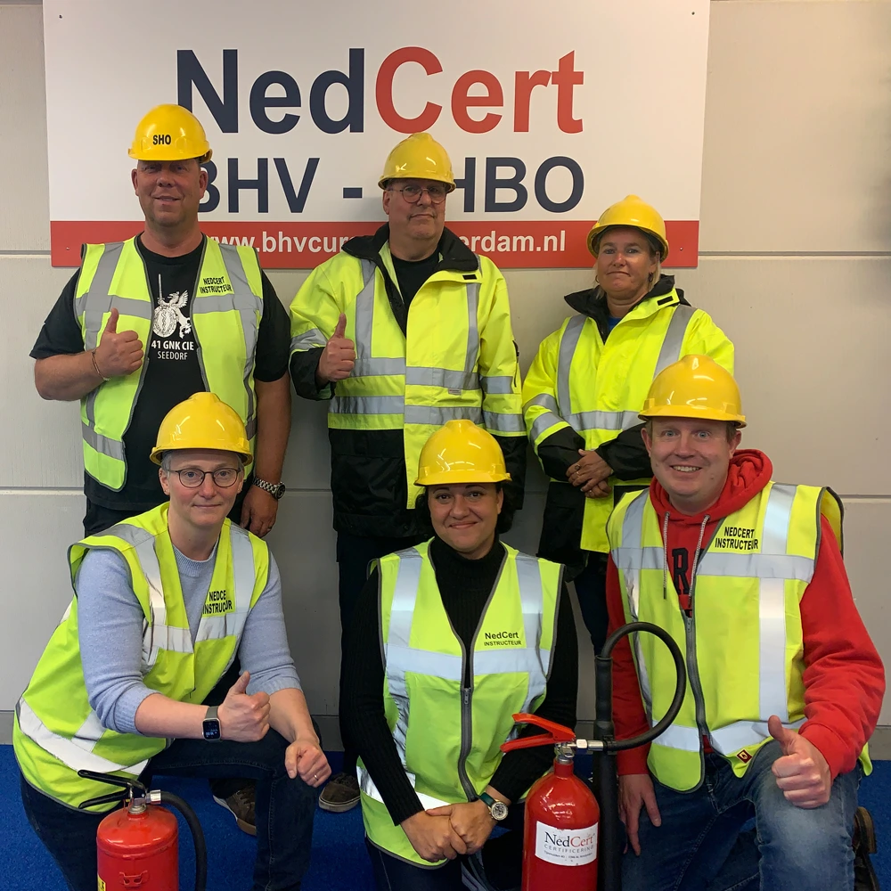 Groep NedCert Experts in veiligheidshesjes met brandblussers, klaar voor BHV- en EHBO-trainingen.
