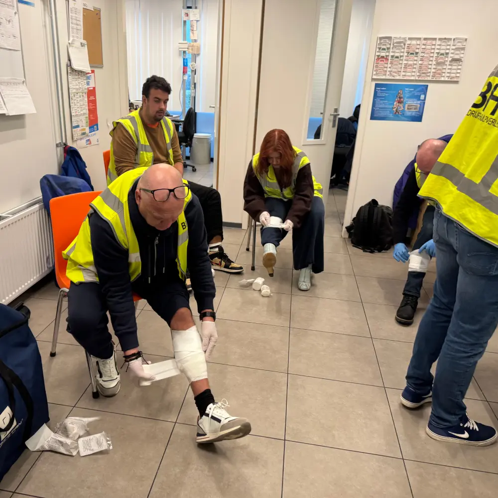 BHV-cursisten oefenen EHBO en verbinden in een smal halletje tijdens een incompany training