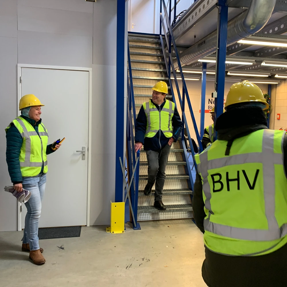 Instructeur met portofoon leidt ontruiming tijdens BHV-training, NedCert Experts.