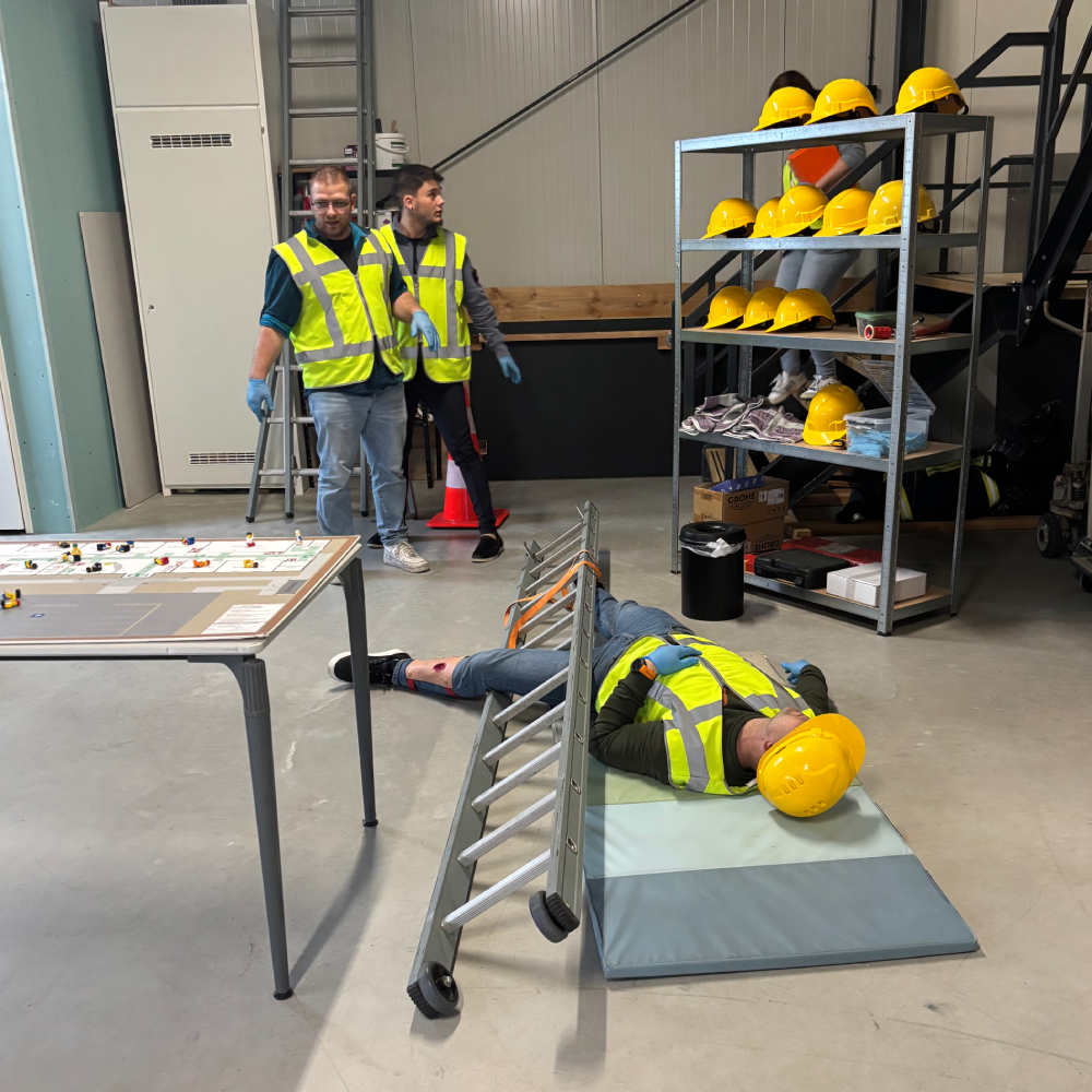 Oefenslachtoffer ligt bewusteloos naast een omgevallen ladder met zijn helm naast zijn hoofd tijdens een SEHSO-cursus van NedCert Experts in Emmen.